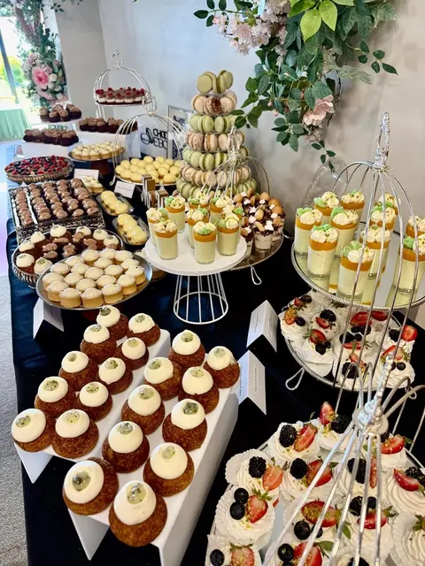 Candy bar cu turn de macarons verzi, pahare cu desert și prăjituri cu fructe de pădure