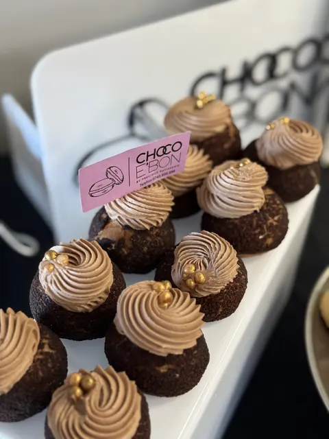 Prăjituri cu cremă de ciocolată și perle aurii, lângă plăcuța Choco e'Bon