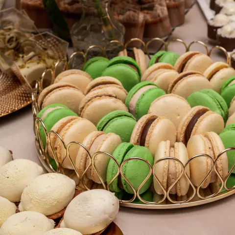 Macarons verzi și crem cu bezele, pe un platou auriu
