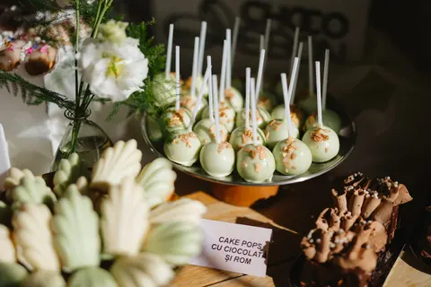 Cake pops verzi pe un platou, lângă flori albe