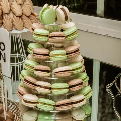 Turn de macarons verzi și crem pe un suport alb